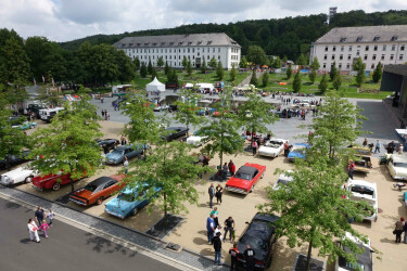 Foto des Parkplatzes mit vielen Oldtimern und Gästen der Route46.