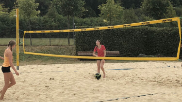 Beachvolleyball Feld mit zwei jungen Spielerinnen.