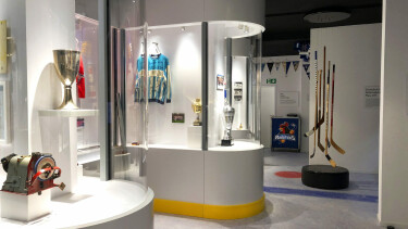 Vitrine mit diversen Exponaten und Pokalen zum Thema Eishockey.