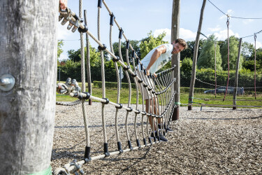 Junger Mann klettert durch den Seilgarten.