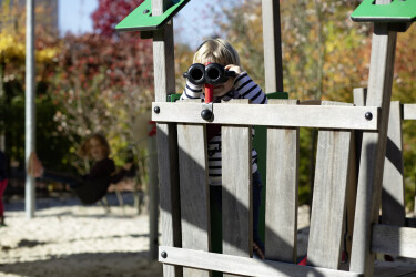 Ein Kind schaut durch ein Fernrohr, das an einem Kletterturm auf dem U3-Spielplatz angebracht ist.