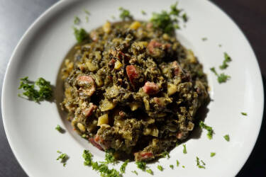Teller mit deftigem Grünkohl-Eintopf mit Kartoffeln, Speck, Kasseler und Mettwurst.