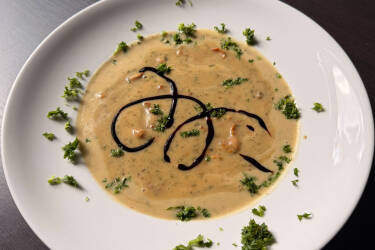 Teller mit cremiger Kartoffelsuppe, Pfifferlingen, Petersilie und einem Spiegel aus Balsamico-Creme.